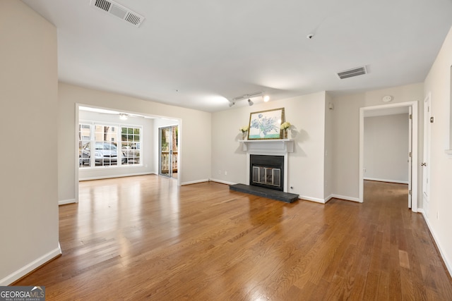 unfurnished living room featuring wood-type flooring and rail lighting