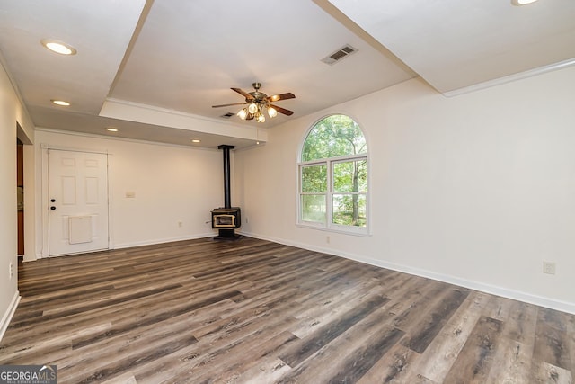 unfurnished living room with a wood stove, ceiling fan, and dark hardwood / wood-style floors