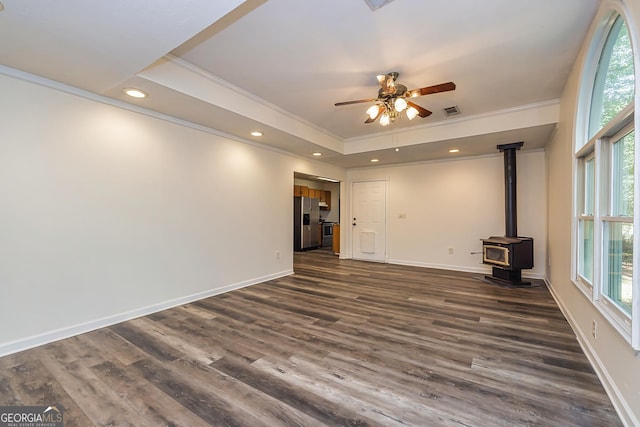 unfurnished living room with dark hardwood / wood-style floors, a wood stove, and a healthy amount of sunlight