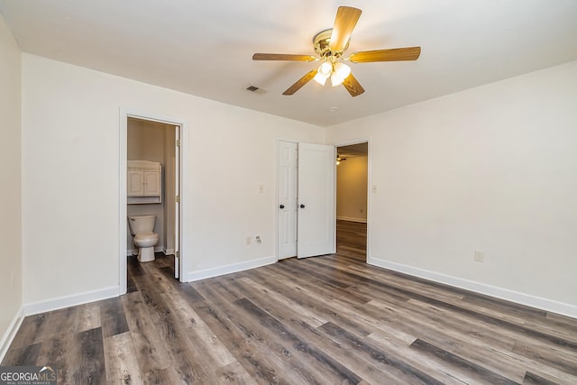 unfurnished bedroom featuring dark hardwood / wood-style floors, ceiling fan, and connected bathroom