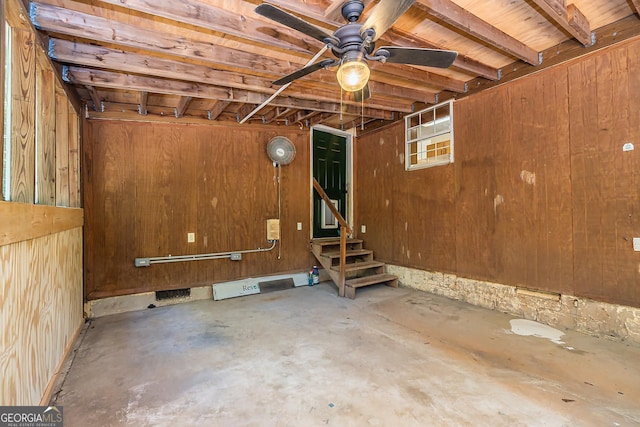 basement featuring ceiling fan, wood walls, and wooden ceiling