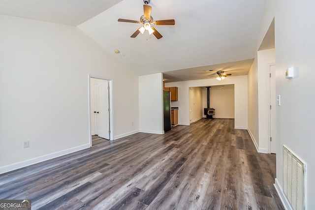 unfurnished living room with lofted ceiling, ceiling fan, a wood stove, and dark wood-type flooring