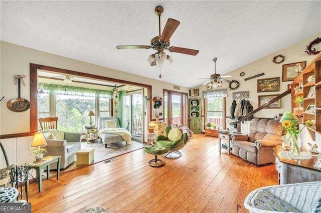 living room with light hardwood / wood-style floors, lofted ceiling, and a textured ceiling