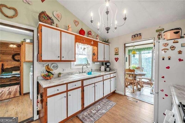 kitchen with decorative light fixtures, light hardwood / wood-style flooring, white cabinets, white fridge, and lofted ceiling