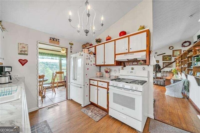 kitchen featuring lofted ceiling, white appliances, white cabinets, light wood-type flooring, and a chandelier