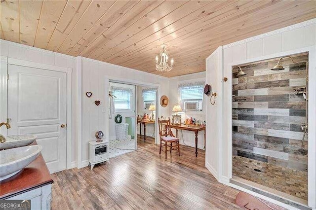 foyer entrance with wood-type flooring, an inviting chandelier, wooden walls, and wood ceiling