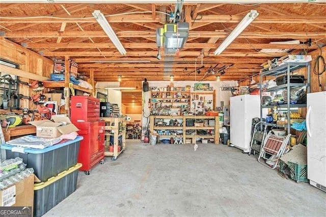 garage with a workshop area, white refrigerator, and a garage door opener