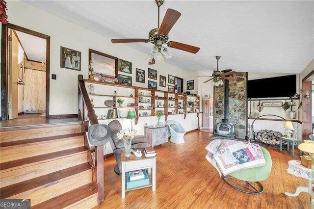 living room featuring a wood stove, lofted ceiling, and hardwood / wood-style flooring