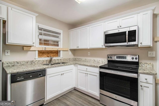 kitchen with sink, light wood-type flooring, light stone counters, white cabinetry, and stainless steel appliances