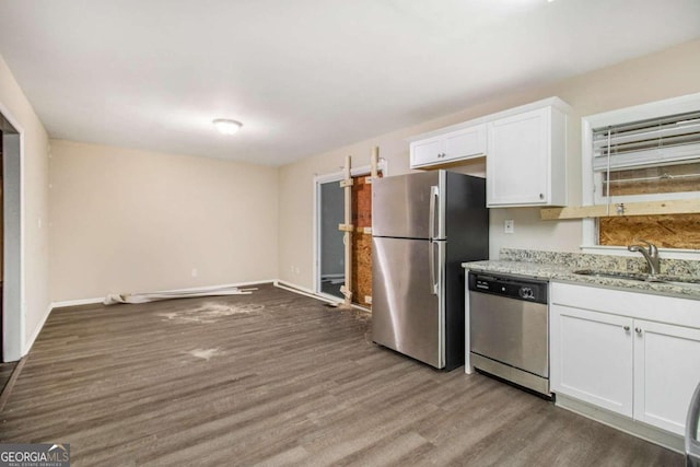 kitchen with white cabinetry, sink, light stone countertops, appliances with stainless steel finishes, and hardwood / wood-style flooring