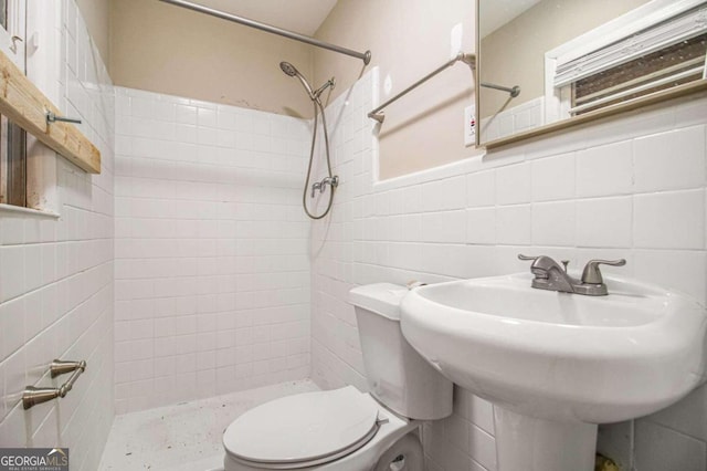 bathroom featuring a tile shower, backsplash, tile walls, and toilet