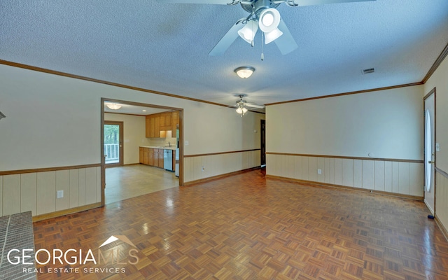 empty room featuring ceiling fan, ornamental molding, a textured ceiling, and parquet flooring