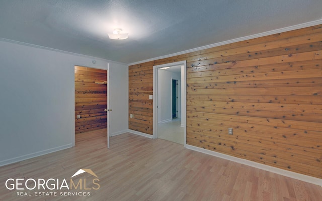 interior space with a closet, wood walls, crown molding, and light wood-type flooring