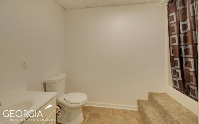 bathroom featuring a drop ceiling, a shower with curtain, tile patterned floors, toilet, and vanity