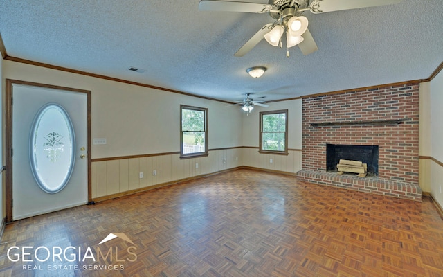 unfurnished living room featuring a fireplace, ceiling fan, crown molding, and a textured ceiling