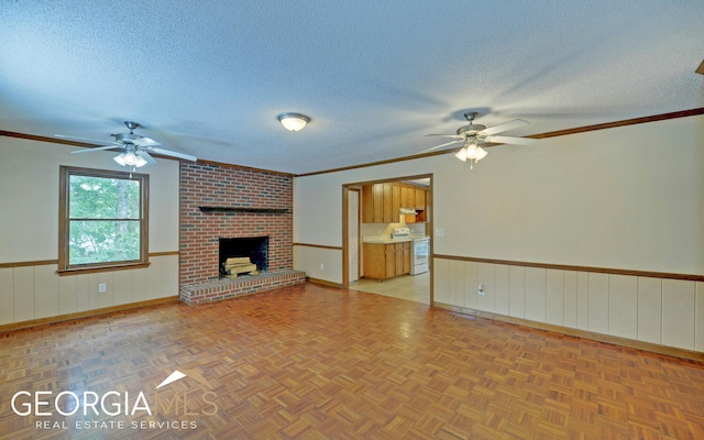 unfurnished living room with crown molding, ceiling fan, a textured ceiling, and a brick fireplace