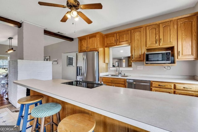 kitchen with ceiling fan, sink, hanging light fixtures, a breakfast bar, and appliances with stainless steel finishes