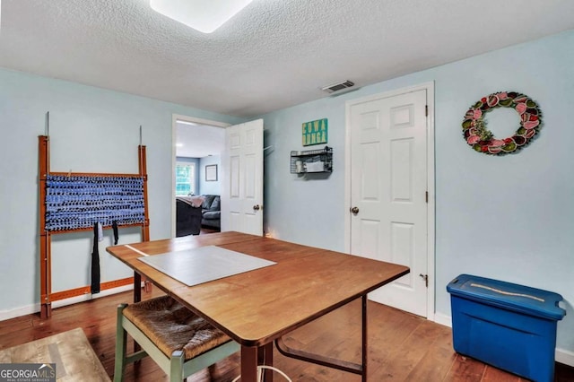 dining space with dark wood-type flooring and a textured ceiling