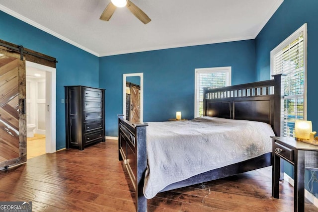 bedroom with ensuite bath, ceiling fan, dark wood-type flooring, crown molding, and a barn door