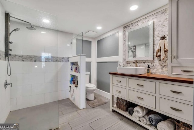 bathroom featuring tiled shower, vanity, and toilet