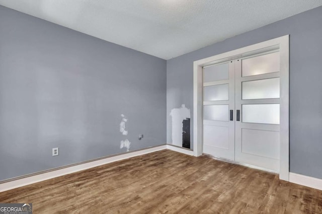 unfurnished bedroom featuring hardwood / wood-style floors, a textured ceiling, and a closet