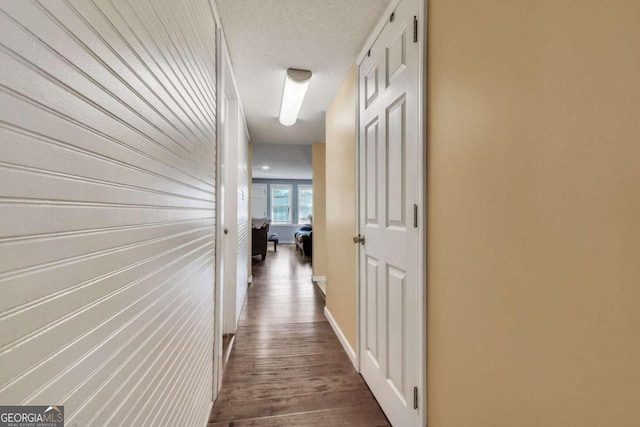 hall with dark hardwood / wood-style flooring and a textured ceiling