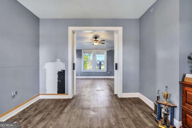 unfurnished living room featuring dark hardwood / wood-style floors, ceiling fan, and a textured ceiling