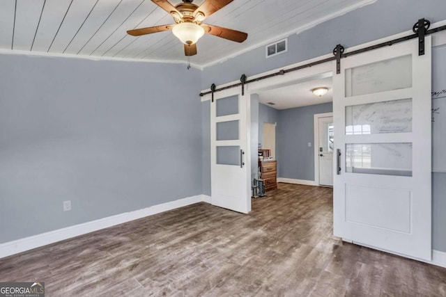 spare room featuring ornamental molding, wood ceiling, ceiling fan, a barn door, and hardwood / wood-style floors