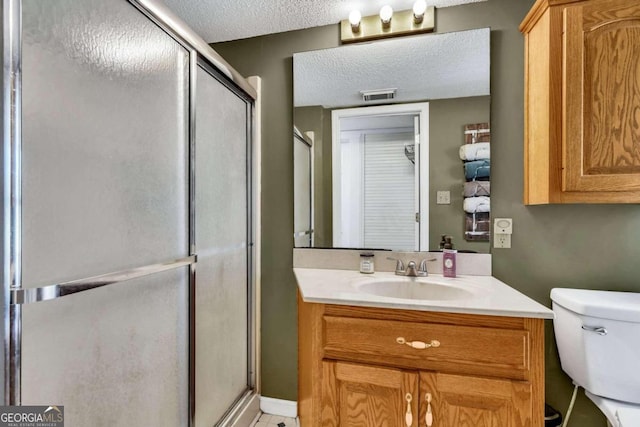 bathroom featuring toilet, vanity, a textured ceiling, and walk in shower