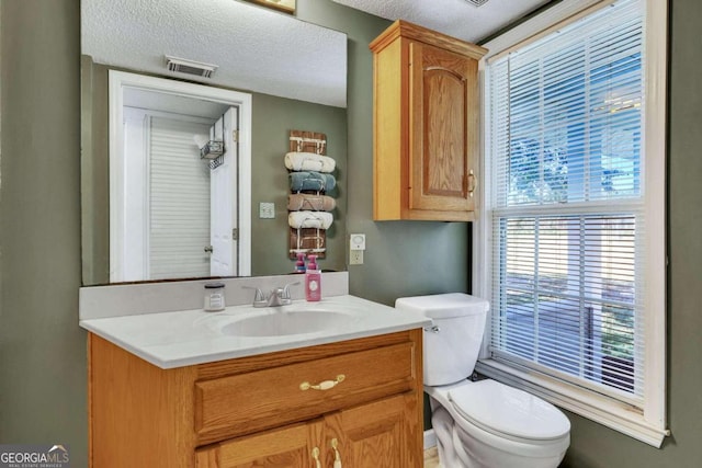 bathroom featuring vanity, a textured ceiling, and toilet