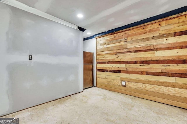 spare room with wood walls and concrete floors