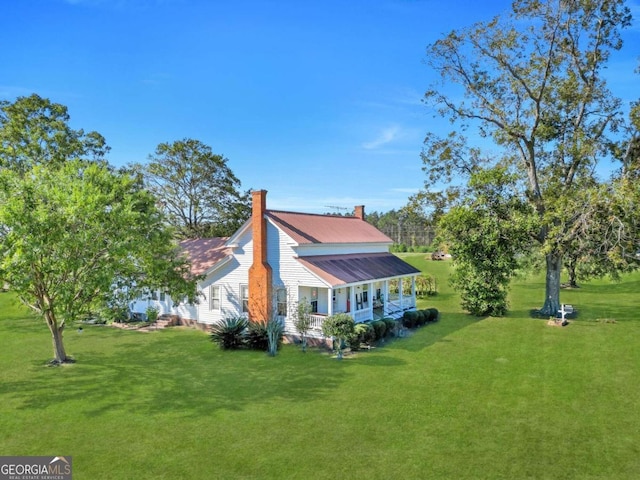 view of side of property with covered porch and a yard