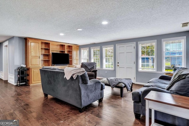 living room with a textured ceiling, dark hardwood / wood-style flooring, and a wealth of natural light