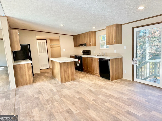 kitchen with black appliances, a textured ceiling, and light wood-type flooring