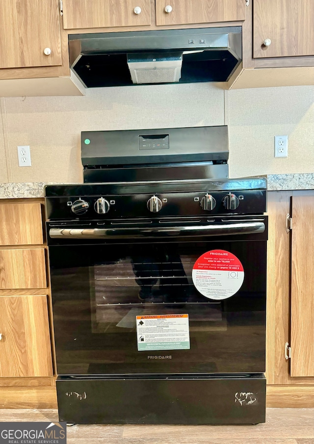 room details featuring black gas range and ventilation hood