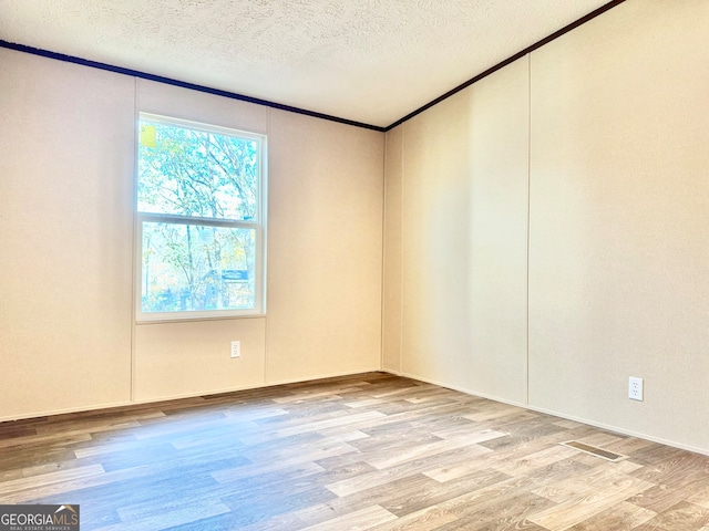 unfurnished room with light hardwood / wood-style floors, crown molding, and a textured ceiling