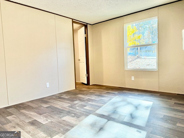 unfurnished room with hardwood / wood-style floors and a textured ceiling