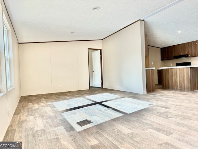 empty room with light hardwood / wood-style flooring, a textured ceiling, and ornamental molding