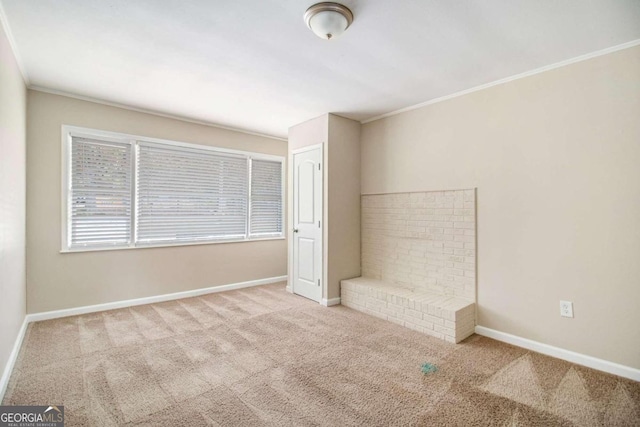 spare room featuring light carpet, a brick fireplace, and ornamental molding