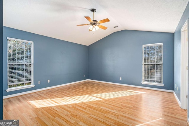 unfurnished room featuring plenty of natural light, ceiling fan, light wood-type flooring, and lofted ceiling