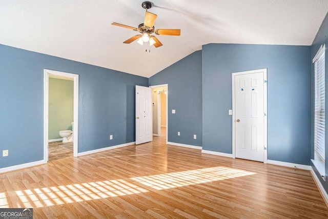 unfurnished bedroom featuring ceiling fan, wood-type flooring, connected bathroom, and lofted ceiling