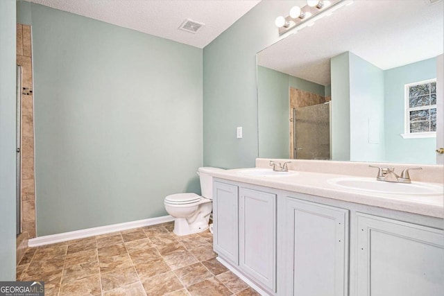 bathroom with vanity, toilet, a shower with door, and a textured ceiling