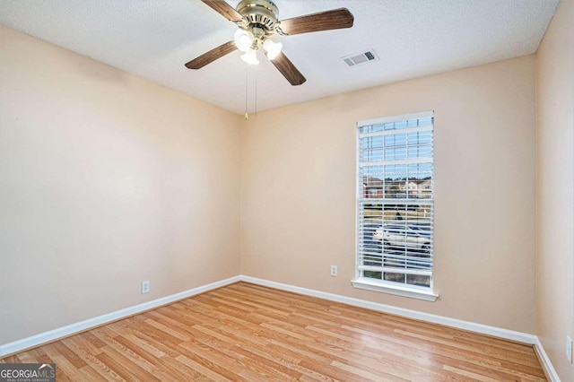 empty room featuring ceiling fan, light hardwood / wood-style floors, and a textured ceiling