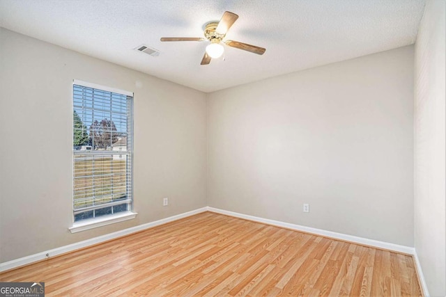 unfurnished room with a textured ceiling, light wood-type flooring, and ceiling fan