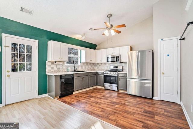 kitchen with appliances with stainless steel finishes, sink, wood-type flooring, white cabinets, and gray cabinets