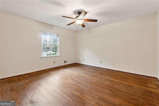 empty room with ceiling fan and dark hardwood / wood-style flooring