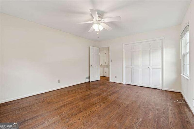 unfurnished bedroom with ceiling fan, a closet, and dark wood-type flooring