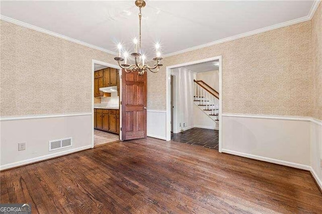 unfurnished dining area featuring dark hardwood / wood-style floors, an inviting chandelier, and crown molding