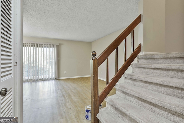 stairway with wood-type flooring and a textured ceiling