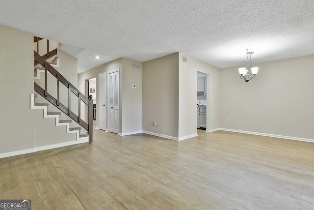 empty room featuring a textured ceiling, sink, light hardwood / wood-style flooring, and a notable chandelier